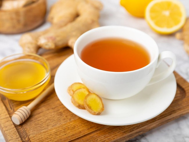 Cup of hot ginger tea with slices of ginger root on wooden background. Warming drink. Alternative medicine. Tea with honey, lemon, ginger and mint. Space for text. Copy space