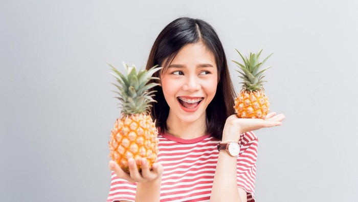Young girl happy smile and cheerful in red dress and hold two pineapple in hand. Concept summer travel.