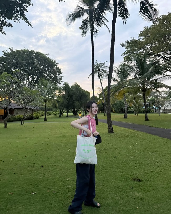 Lewat akun Instagram-nya, Shin Si Ah memamerkan suasana tropis Bali dengan pepohonan dan keindahan langit menjelang sunset. Sang aktris tampil kasual dengan sleveeless shirt berwarna pink dan baggy jeans. Kontras dengan penampilannya memakai jas snelli di Resident Playbook. Foto: Instagram