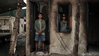Rahmat bersama saudaranya berpose di dalam rumahnya yang terbakar. Seluruh keluarganya aman.