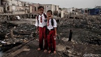 Ahmad dan Adi berpose tanpa sepatu karena sepatu mereka terbakar dam kini mereka belum bisa membeli sepatu lagi karena keterbatasan ekonomi.  