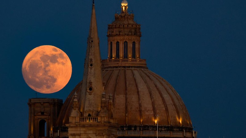 A full moon known as the Strawberry Moon rises behind the steeple of St Paul's Anglican Cathedral and the dome of the Basilica of Our Lady of Mount Carmel in Valletta, as seen from Sliema, Malta, June 10, 2025.   REUTERS/Darrin Zammit Lupi