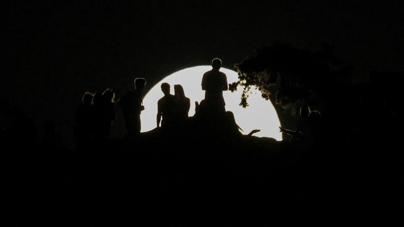 People watch the rising “Strawberry Moon” from Areopagus Hill in Athens, Greece, June 10, 2025. REUTERS/Louisa Gouliamaki     TPX IMAGES OF THE DAY