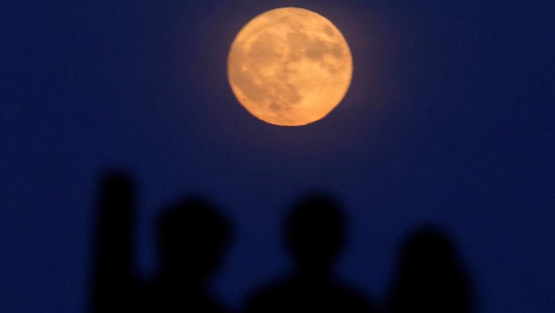 People watch the full moon known as the Strawberry Moon rise, as seen from Hampstead Heath, in London, Britain, June 10, 2025.  REUTERS/Peter Cziborra