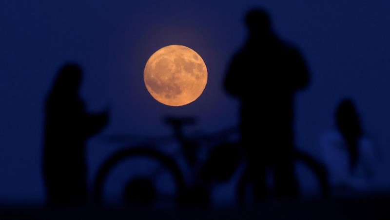 People watch the full moon known as the Strawberry Moon rise, as seen from Hampstead Heath, in London, Britain, June 10, 2025.  REUTERS/Peter Cziborra