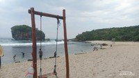 Wahana ayunan kayu dipinggir pantai