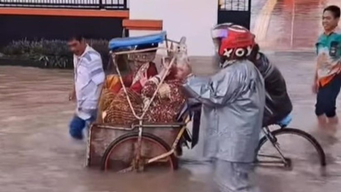 Pengantin bernama Ikhsan dan Sunarti di Bulukumba, Sulawesi Selatan (Sulsel), tetap menggelar resepsi pernikahan saat banjir. Keduanya pun naik becak menerobos banjir menuju pelaminan.