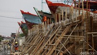 Pekerja menggunakan bahan beton bertulang untuk membangun dinding tanggul sebagai pelindung utama permukiman dari kenaikan muka air laut.