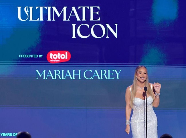 Pada penampilan berikutnya, Mariah yang akan menggelar konser di Jakarta pada 4 Oktober 2025 kembali mengundang decak kagum lewat gaun korset putih berpayet dan aksesori berlian berbentuk tetesan air mata yang menghiasi leher, telinga, dan pergelangan tangannya. (Foto: Kevin Winter/Getty Images)