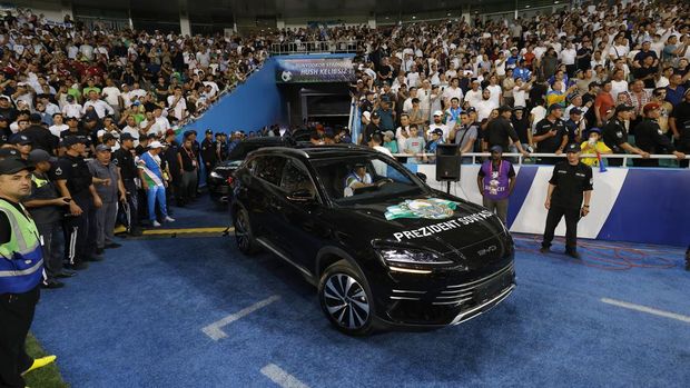 Uzbekistan President Shavkat Mirziyoyev is driven onto the pitch to honor the national football team after securing a spot at the 2026 FIFA World Cup