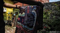 Seorang perajin tampak tekun membatik di halaman rumahnya. Upaya pelestarian Batik Tugu kini mendapat dukungan dari pemerintah daerah Jakarta Utara serta komunitas budaya lokal.