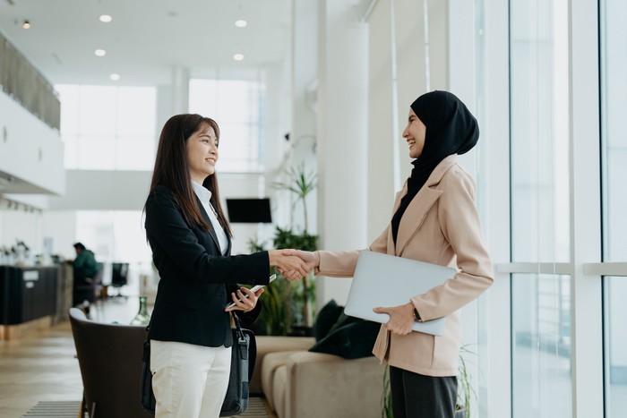 Two Asian businesswomen shake hands after a successful meeting