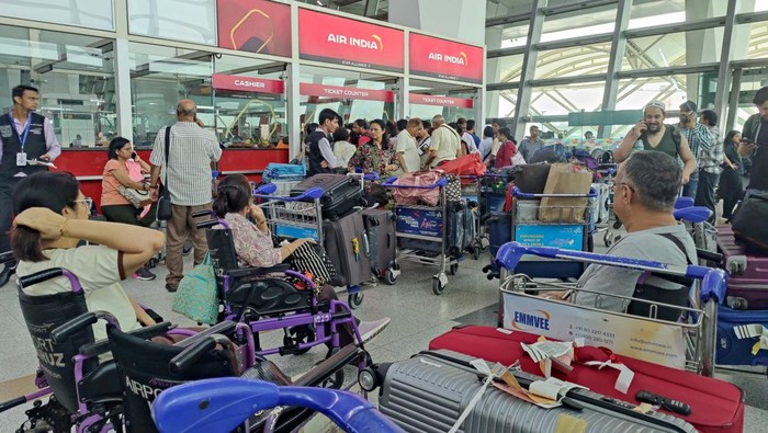 Konflik Israel-Iran ganggu rute udara. Penumpang menumpuk di loket Air India, antre ubah jadwal. Maskapai alihkan penerbangan demi keselamatan.