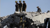 Petugas penyelamat bekerja di lokasi dampak setelah serangan rudal dari Iran ke Israel, di Rishon LeZion, Israel, pada 14 Juni 2025.Foto: REUTERS/Ronen Zvulun