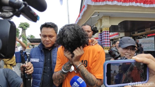 NPJ, WN Australia yang kedapatan membawa kokain saat patroli (hunting) lalu lintas di Pererenan, Mengwi, Badung, menutup wajah saat digiring, Sabtu (14/6/2025). (Agus Eka)