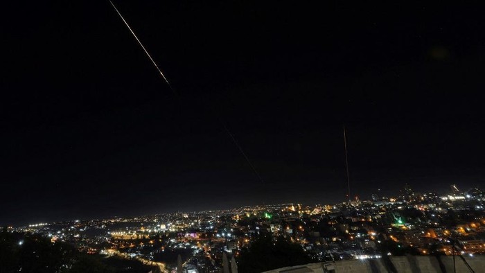 This picture shows a rocket trail from Israels Iron Dome missile defense system batteries fired to intercept rockets launched from Iran above the Dome of the Rock in the al-Aqsa mosque compound in Jerusalems Old City on June 13, 2025. Air raid sirens sounded in Jerusalem and loud blasts were heard on June 13, AFP journalists reported, as the Israeli military said it had detected a missile launched from Iran. (Photo by AHMAD GHARABLI / AFP)