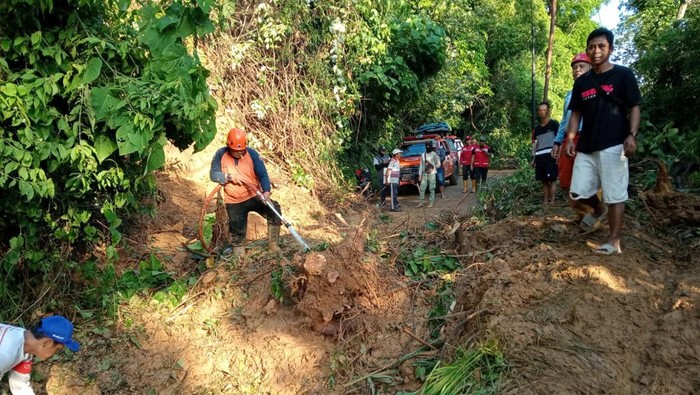 Warga membersihkan material banjir yang menutup akses keluar masuk Desa Pujiharjo Malang.