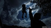Dengan peralatan lengkap dan prosedur keamanan ketat, anak-anak satu per satu meluncur di udara sambil berteriak antusias.