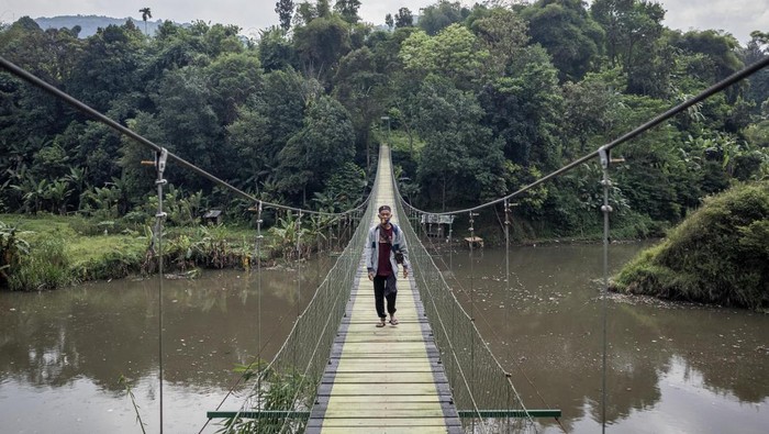 Warga berjalan di atas Jembatan Gantung Citarum di Cihampelas, Kabupaten Bandung Barat, Jawa Barat, Minggu (15/6/2025). Bupati Bandung Barat Jeje Ritchie Ismail menyatakan jembatan gantung yang memiliki panjang sekitar 100 meter dan menghubungkan Desa Pataruman dengan Desa Margaasih tersebut menjadi salah satu potensi ekowisata yang dapat dimanfaatkan serta dikelola oleh Koperasi Desa Merah Putih di wilayah itu. ANTARA FOTO/Abdan Syakura