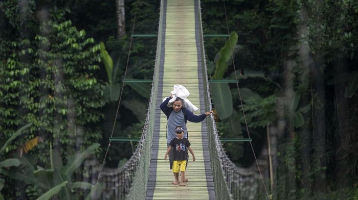 Warga berjalan di atas Jembatan Gantung Citarum di Cihampelas, Kabupaten Bandung Barat, Jawa Barat, Minggu (15/6/2025). Bupati Bandung Barat Jeje Ritchie Ismail menyatakan jembatan gantung yang memiliki panjang sekitar 100 meter dan menghubungkan Desa Pataruman dengan Desa Margaasih tersebut menjadi salah satu potensi ekowisata yang dapat dimanfaatkan serta dikelola oleh Koperasi Desa Merah Putih di wilayah itu. ANTARA FOTO/Abdan Syakura