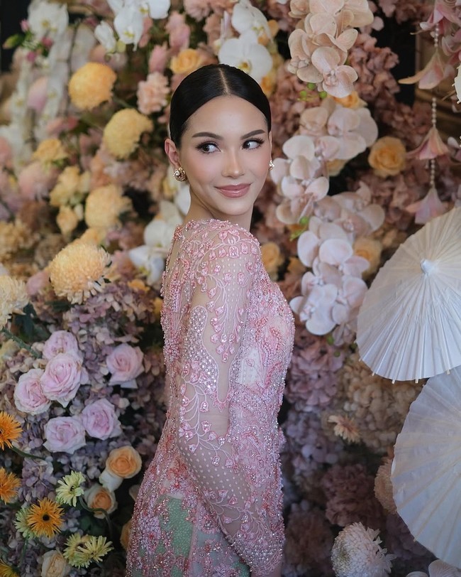 Kebaya dipenuhi sulaman berbentuk floral dan taburan payet kristal yang dirancang rumit, menciptakan kilau halus yang terlihat dramatis namun tetap lembut di bawah cahaya. Sentuhan warna keperakan dan nuansa fuchsia muda memperkaya tekstur busana. Foto: Instagram/@rhay_david