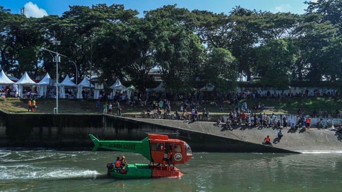 Serunya Akhir Pekan! Anak-Anak Naik 'Helikopter Air' di BKT Suasana akhir pekan di kawasan Banjir Kanal Timur (BKT) tampak meriah dan berbeda dari biasanya. Anak-anak tertawa riang saat menaiki wahana unik berbentuk