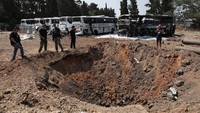 Sirene serangan udara meraung di Tel Aviv pada Selasa (17/6) pagi, sementara beberapa ledakan juga terdengar. Di Herzliya, bus dan kawah yang rusak dapat dilihat dari tempat parkir di dekat apa yang tampak seperti awan asap hitam yang panjang dan mengalir. Foto: REUTERS/Ronen Zvulun
