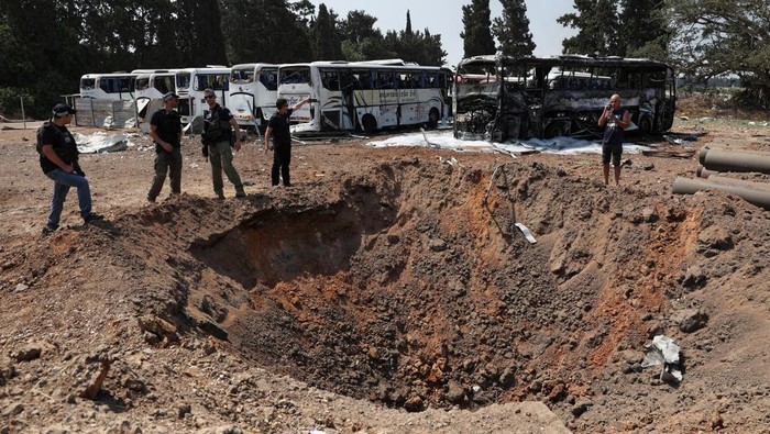 Jejak Serangan Rudal Iran di Herzliya Israel Tengah Police officers stand next to a crater at an impact site following a missile attack from Iran, in Herzliya, Israel, June 17, 2025. REUTERS/Ronen Zvulun