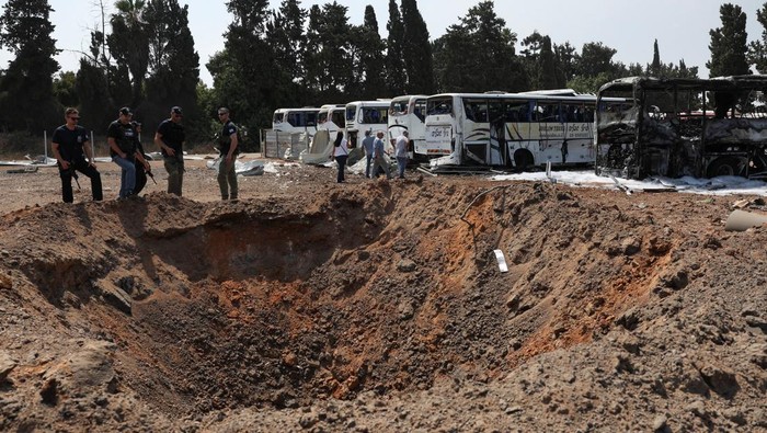 Police officers stand next to a crater at an impact site following a missile attack from Iran, in Herzliya, Israel, June 17, 2025. REUTERS/Ronen Zvulun