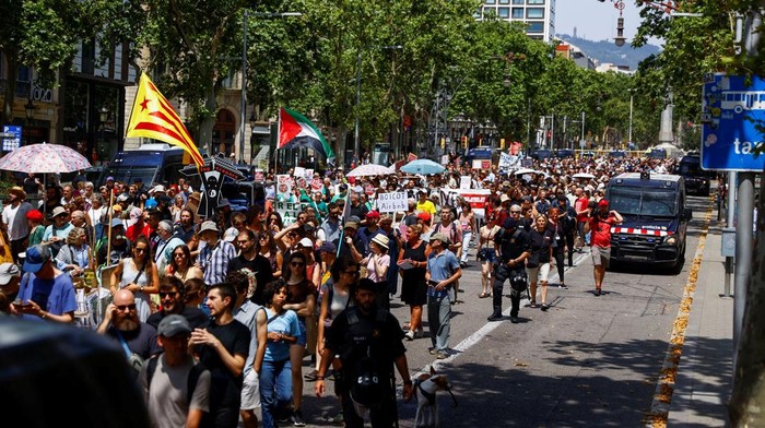 Warga Barcelona Gerah Diserbu Pelancong, Usir Turis dengan Semprotan Demonstrators hold a banner which reads