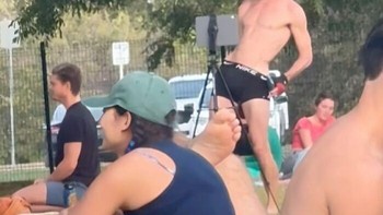 Influencer bertelanjang dada, memakai topi, dan celana pendek hitam tengah melakukan aksi di taman, menarik perhatian orang-orang yang sedang duduk.Foto: Boredpanda