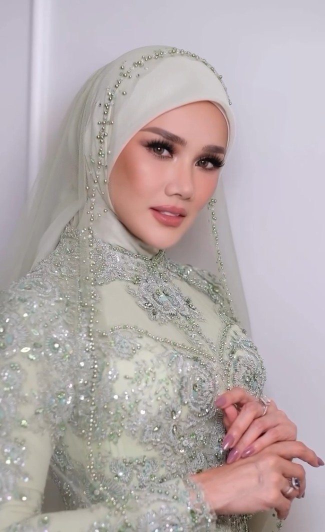 Tampil dalam balutan hijab dan busana payet sarat detail, riasannya mencerminkan gaya glamor tapi tidak berlebihan. Foto: Instagram/@rezaazrumakeup