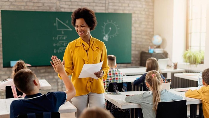 Guru dan siswa sedang belajar di ruang kelas