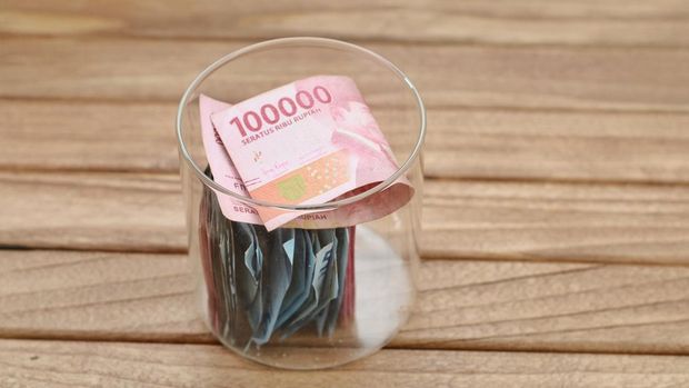 Indonesian currency rupiah in a glass jar on a wooden table