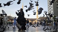 Beberapa orang berdiri dan berinteraksi di antara kawanan merpati yang menjadi salah satu ikon visual kawasan sekitar Masjid Nabawi. Foto: ANTARA FOTO/Andika Wahyu