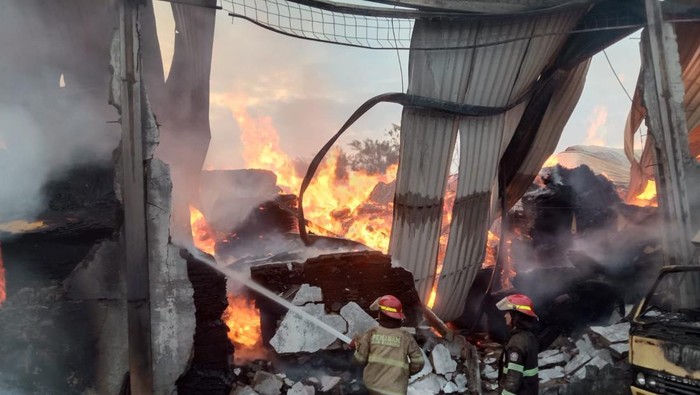 Petugas damkar saat melakukan pemadaman gudang tripleks yang terbakar.