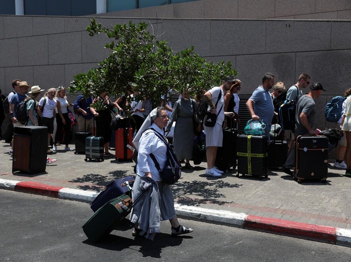 Takut Rudal Iran, WNA Ramai-ramai Kabur dari Israel A man holds passports, as people of foreign nationalities gather to leave Israel on buses via Egypt, following a missile attack from Iran, in Tel Aviv, Israel, June 17, 2025. REUTERS/Ronen Zvulun