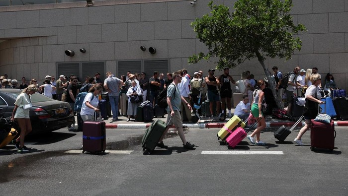 A man holds passports, as people of foreign nationalities gather to leave Israel on buses via Egypt, following a missile attack from Iran, in Tel Aviv, Israel, June 17, 2025. REUTERS/Ronen Zvulun