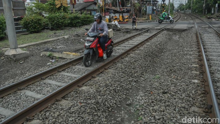 Pengendara melintas di jalur rel kereta api Kawasan Matraman, Jakarta, Rabu (18/6/2025).