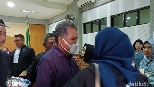 Mantan Bupati Lobar Zaini Arony (memakai baju warna biru dan masker putih) saat menghampiri keluarganya usai sidang eksepsi di Pengadilan Tipikor Mataram, Kamis (19/6/2025). (Foto: Abdurrasyid Efendi/detikBali).