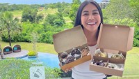 Terlihat pose cantik saat wanita kelahiran 1978 itu menikmati donat. Ia tersenyum sambil menggigit donat topping cokelat. Foto: Instagram @denadaindonesia