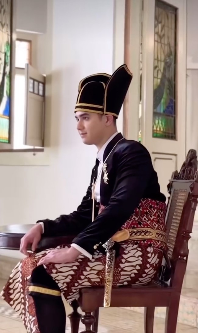 Al mengenakan beskap hitam berkancing emas. Beskap tersebut dihiasi dengan bros emas berbentuk seperti bintang di dada kiri. Penampilannya itu kemudian dilengkapi dengan kain batik motif parang sebagai bawahannya, serta blangkon model kuluk kanigara berwarna hitam dan garis emas. Foto: Instagram/@thebridedept