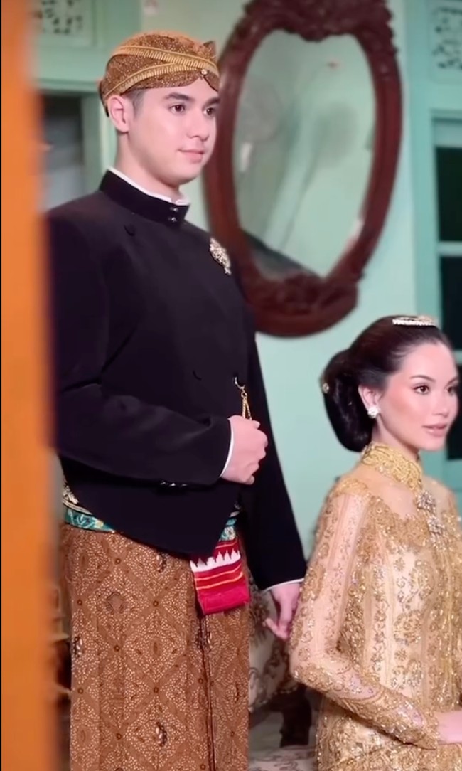 Tak kalah elegan dari look sebelumnya, di look ketiga Al dan Alyssa kembali tampil memukau. Al mengenakan beskap hitam dipadukan dengan kain lilit batik berwarna coklat. Penampilannya lengkap dengan blangkon yang menutup kepalanya. Foto: Instagram/@thebridedept