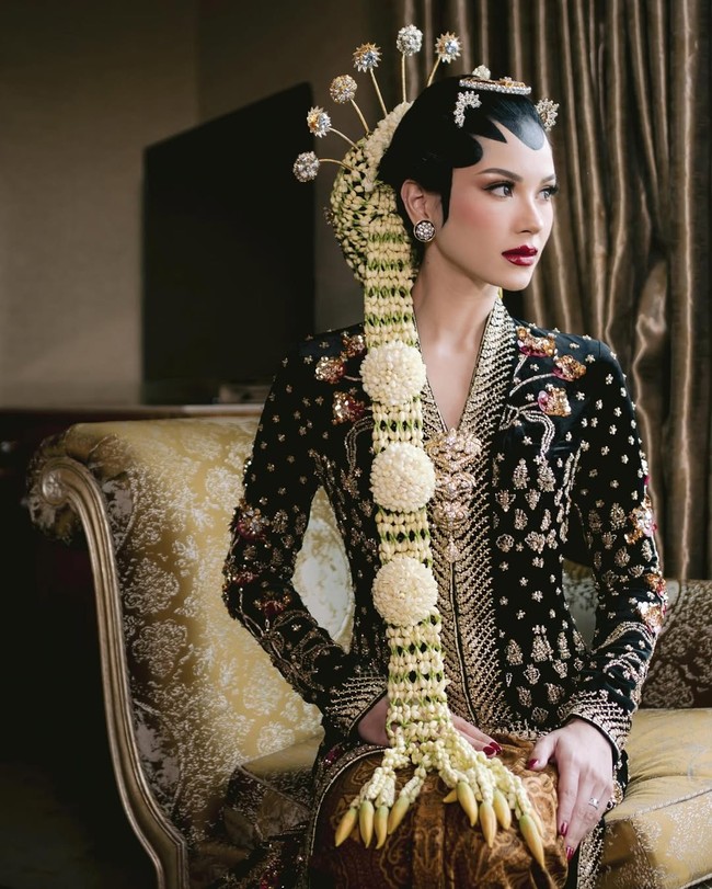 Kebaya panjang hitam dengan detail payet dan bordir emas membuat tampilannya terlihat megah dan dramatis. Dipadankan dengan kain batik bermotif klasik dan sanggul Jawa lengkap dengan paes dan ronce melati panjang, Alyssa terlihat bak putri keraton. Aksesori seperti cunduk mentul juga memberi sentuhan tradisional yang sarat makna. Foto: Instagram/@alyssadaguise @venemapictures