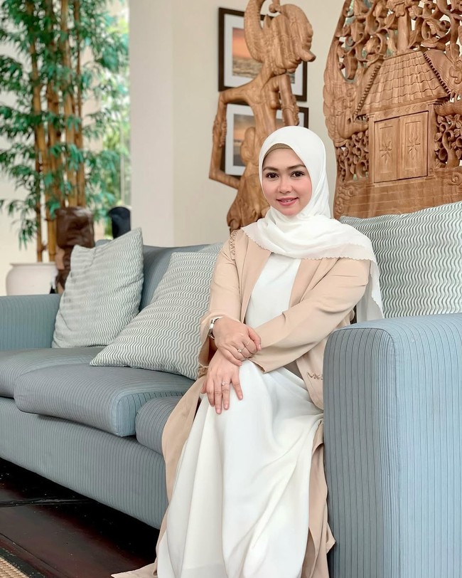 Padu padan long outer cream dan dress ala Lala Nurlela ini bisa membuat penampilan kamu semakin elegan. Ia memadukannya dengan hijab segi empat putih.  Foto: Dok. Instagram @lala_nurlelaa.