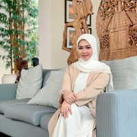 Padu padan long outer cream dan dress ala Lala Nurlela ini bisa membuat penampilan kamu semakin elegan. Ia memadukannya dengan hijab segi empat putih.  Foto: Dok. Instagram @lala_nurlelaa.