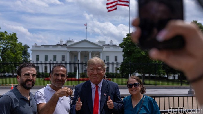 Seorang pria mengenakan topeng mirip Donald Trump beraksi di depan Gedung Putih. Aksi itu mencuri perhatian di tengah suasana politik AS yang dinamis.