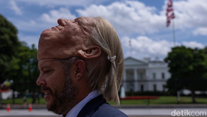 Seorang pria mengenakan topeng mirip Donald Trump beraksi di depan Gedung Putih. Aksi itu mencuri perhatian di tengah suasana politik AS yang dinamis.