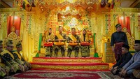 Prosesi penabalan gelar adat yang dilakukan secara khidmat dan penuh dengan tradisi Melayu dengan latar belakang kuning keemasan. (Dok Diskominfotik Pekanbaru)