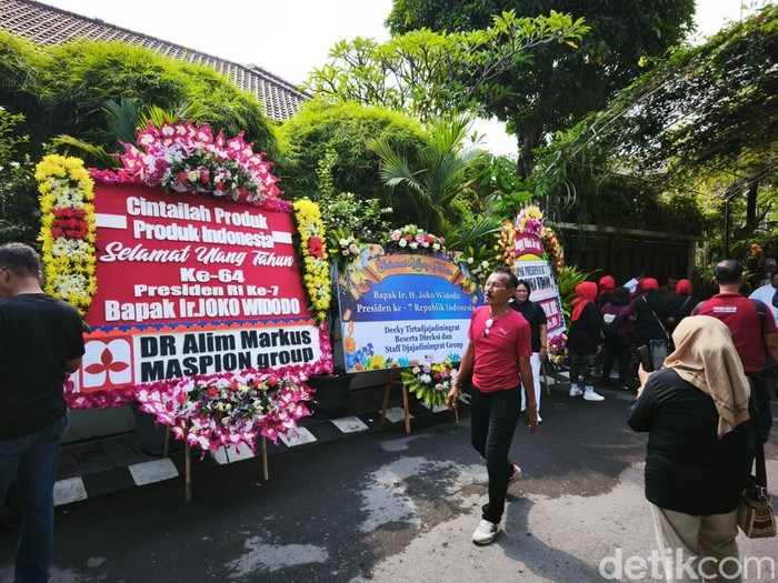 Karangan bunga ucapan selamat ulang tahun ke-64 hingga sosok pria mirip Jokowi asal Bandung, di depan rumah Jokowi di Kelurahan Sumber, Banjarsari, Solo, Sabtu (21/6/2025).